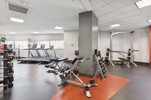 gym featuring a paneled ceiling, visible vents, and baseboards