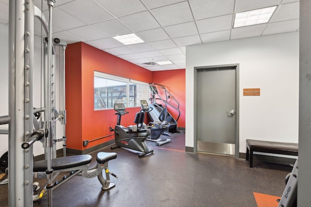 workout area with visible vents, baseboards, and a drop ceiling