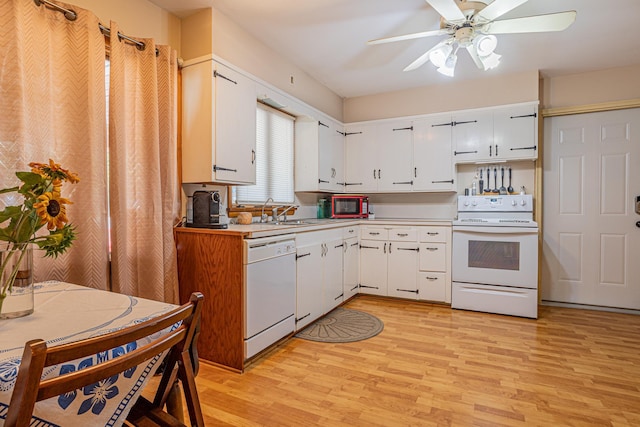 kitchen with light wood-type flooring, white appliances, light countertops, and a sink