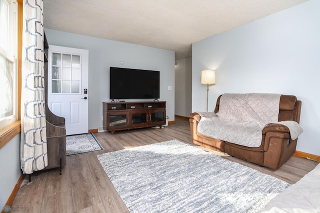 living room with a textured ceiling, wood finished floors, and baseboards