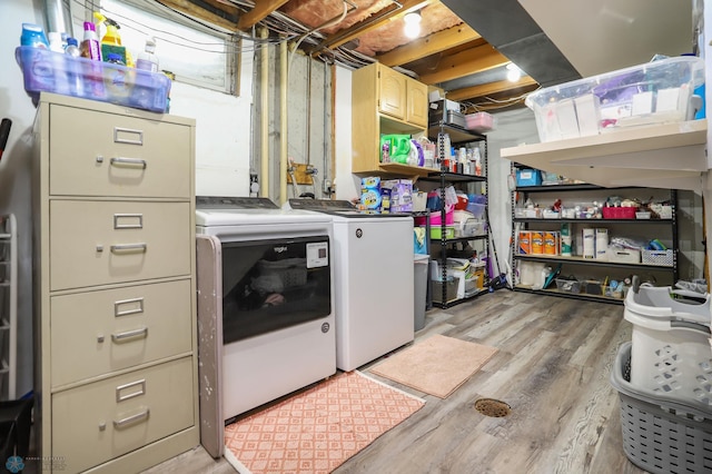 clothes washing area featuring light wood-type flooring, washer and dryer, and laundry area