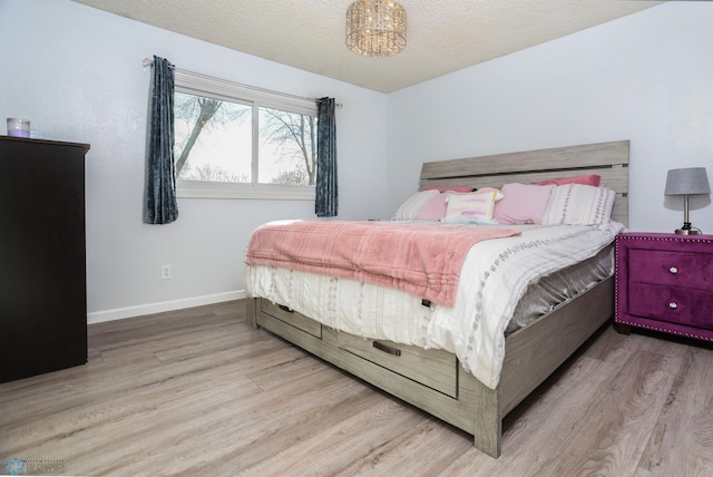 bedroom featuring a textured ceiling, wood finished floors, and baseboards