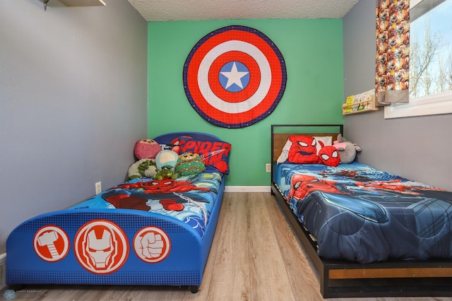 bedroom with a textured ceiling, baseboards, and wood finished floors