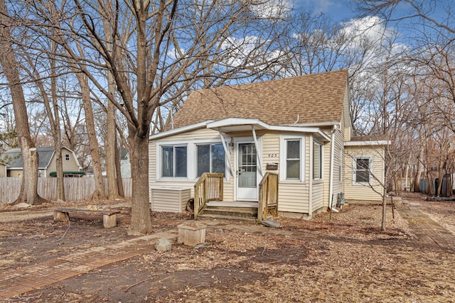 view of front of property with a shingled roof and fence