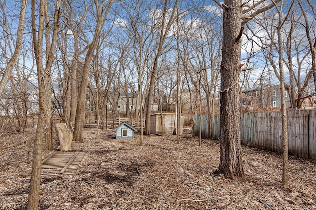 view of yard with a fenced backyard, a storage unit, and an outbuilding