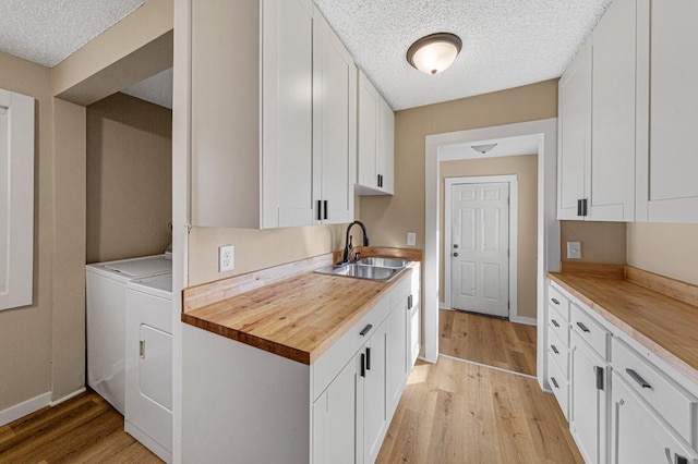 kitchen featuring separate washer and dryer, a sink, butcher block counters, and light wood-style floors