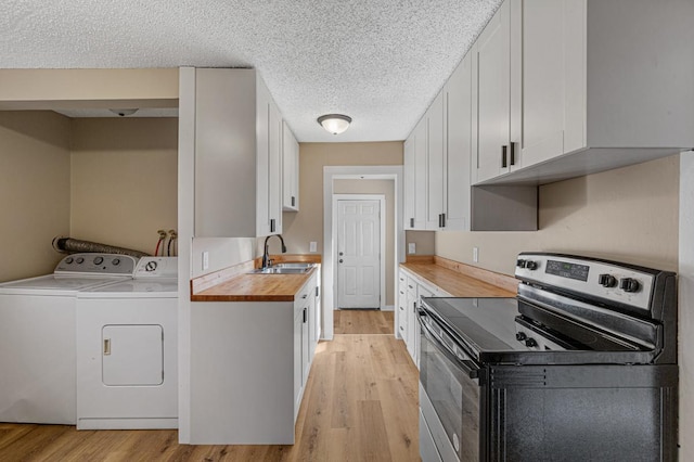 kitchen with light wood-style floors, stainless steel electric range oven, a sink, and washing machine and clothes dryer