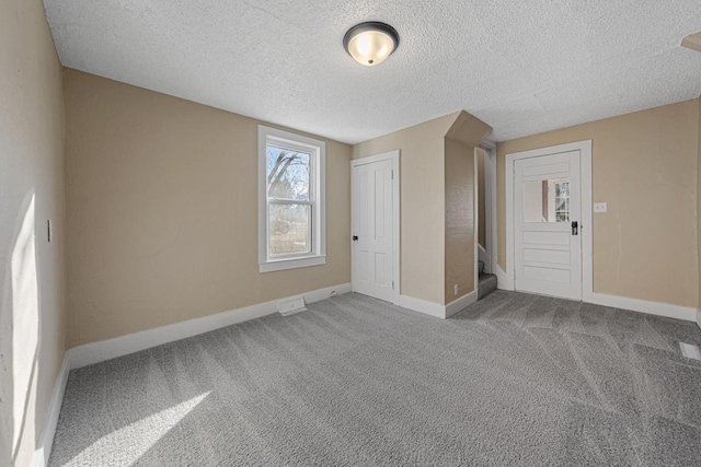 interior space with a textured ceiling, stairs, baseboards, and carpet flooring