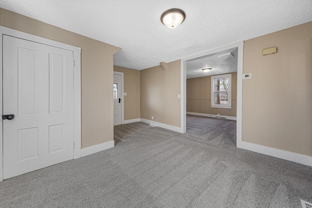 carpeted spare room featuring baseboards and a textured ceiling