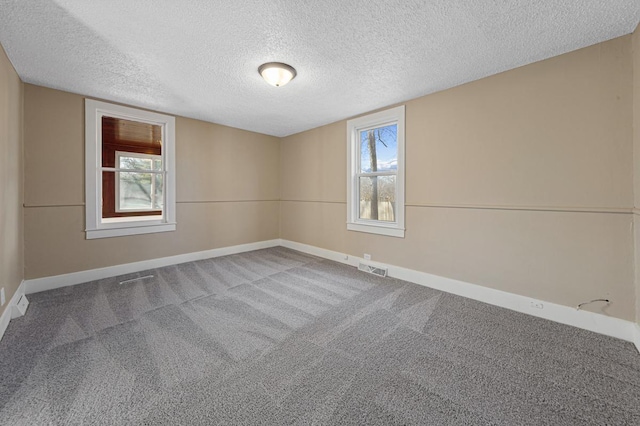 carpeted empty room with visible vents, baseboards, and a textured ceiling