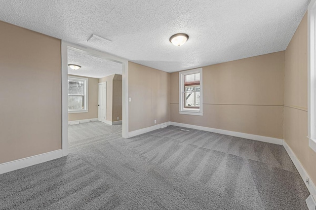 carpeted empty room featuring a textured ceiling and baseboards