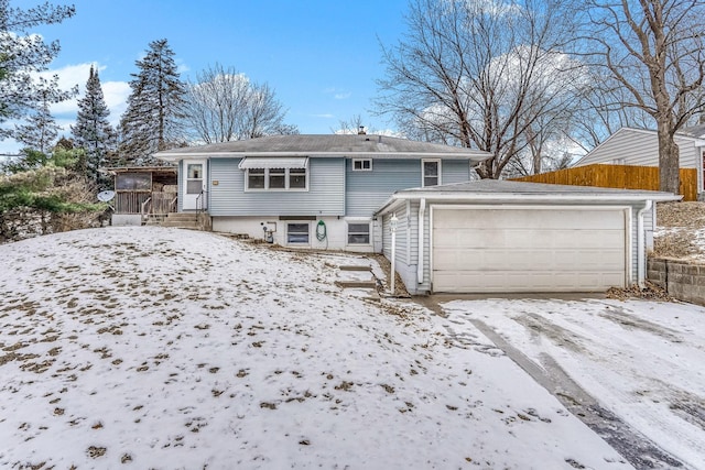 snow covered back of property with fence and a detached garage