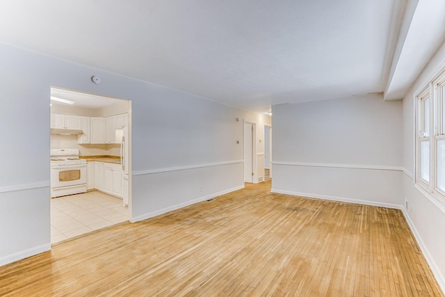 empty room featuring light wood finished floors and baseboards