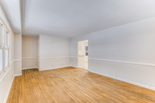 spare room with baseboards, a healthy amount of sunlight, visible vents, and light wood-style floors