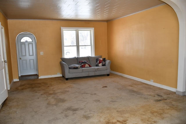 carpeted foyer entrance with arched walkways, ornamental molding, and baseboards