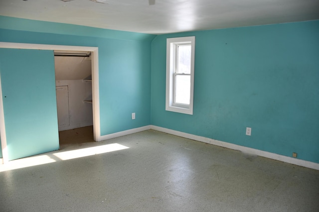 unfurnished bedroom featuring lofted ceiling, a closet, and baseboards