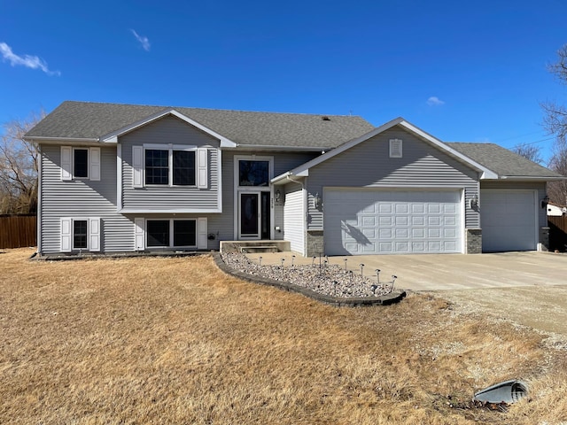 split level home featuring driveway, a shingled roof, a front lawn, and an attached garage