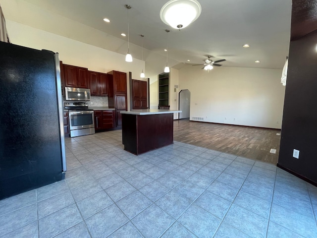 kitchen with light tile patterned floors, arched walkways, appliances with stainless steel finishes, open floor plan, and light countertops