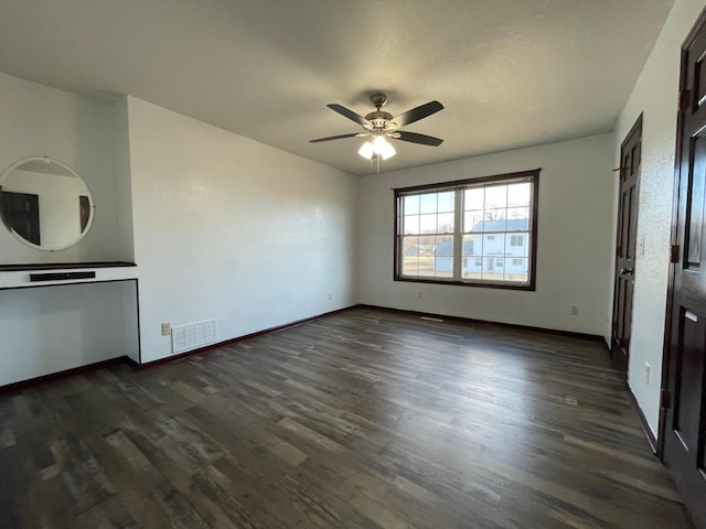 interior space with baseboards, visible vents, and dark wood-style flooring