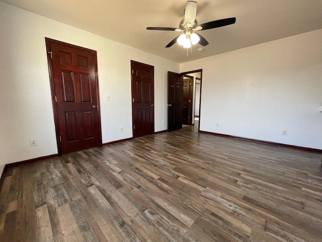 unfurnished bedroom featuring dark wood-type flooring, a ceiling fan, and baseboards