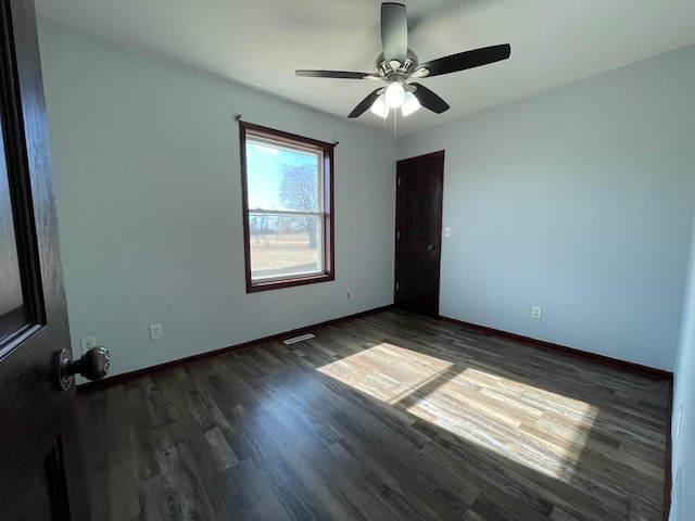 spare room featuring dark wood-style floors, ceiling fan, visible vents, and baseboards