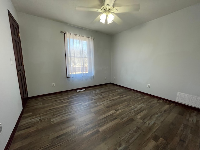 empty room featuring dark wood-style floors, ceiling fan, visible vents, and baseboards