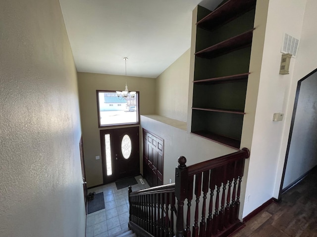 entryway with a notable chandelier, a towering ceiling, and baseboards