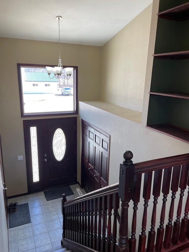 tiled entryway with stairway and a notable chandelier