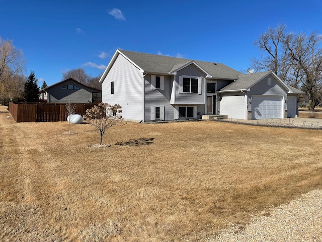 view of front facade with an attached garage, fence, driveway, roof with shingles, and a front yard