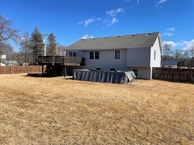 rear view of property featuring a deck, a lawn, and a fenced backyard