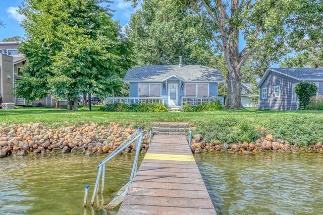 view of dock with a lawn and a water view