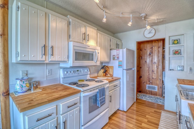 kitchen featuring light wood-type flooring, white appliances, visible vents, and a textured ceiling