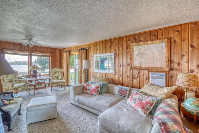 carpeted living room with wood walls, ceiling fan, and a textured ceiling