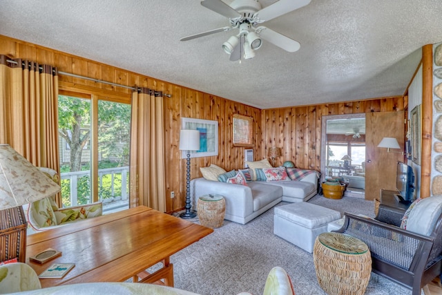 living area with a textured ceiling, wooden walls, and carpet flooring