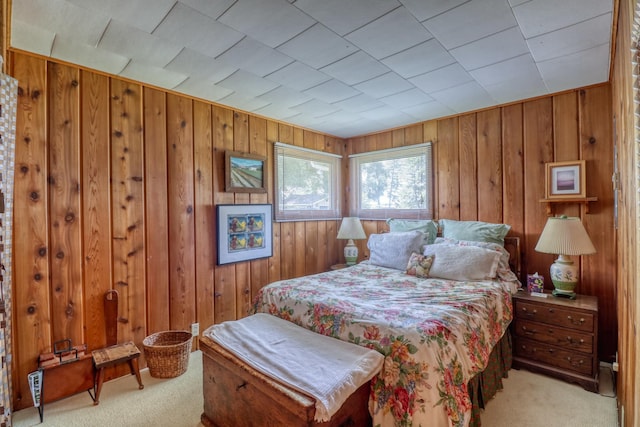 bedroom featuring light colored carpet and wooden walls