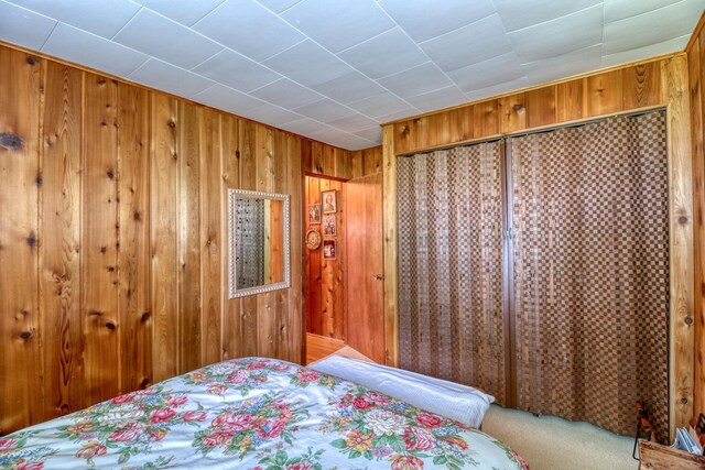 carpeted bedroom featuring wood walls