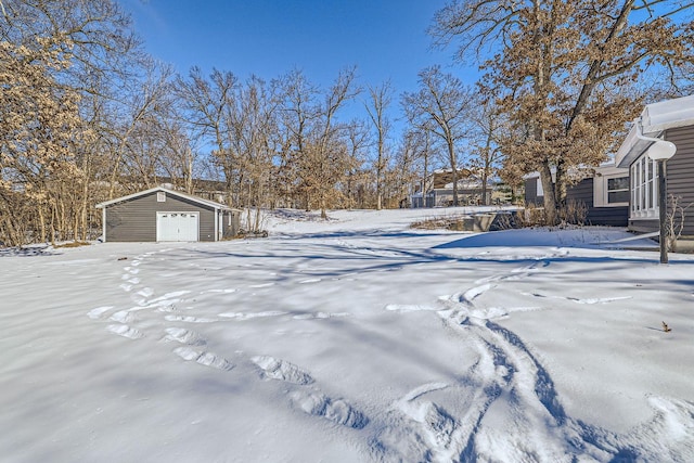 yard layered in snow with a garage and an outdoor structure