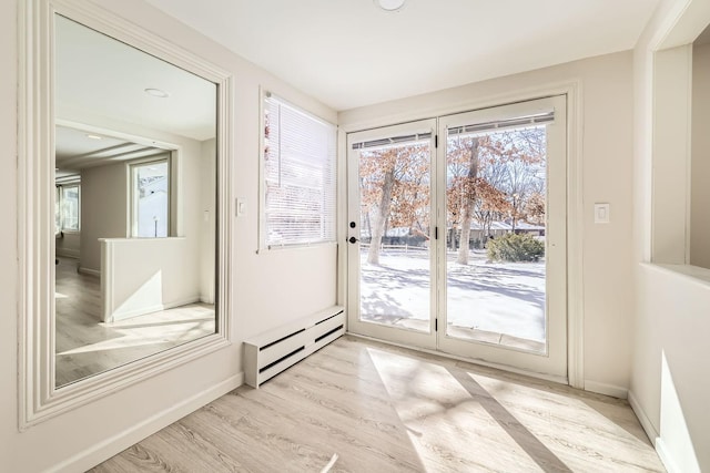 entryway featuring a baseboard heating unit, light wood-style flooring, and baseboards