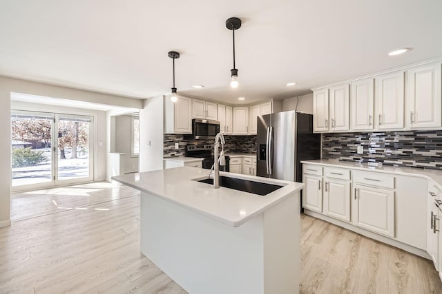 kitchen with tasteful backsplash, appliances with stainless steel finishes, light countertops, light wood-type flooring, and a sink