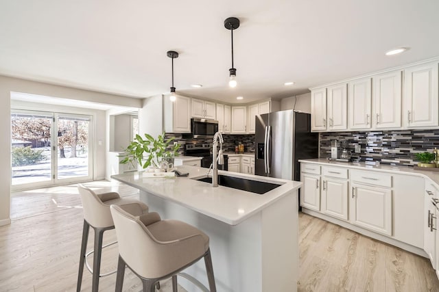 kitchen with light countertops, appliances with stainless steel finishes, light wood-type flooring, and decorative backsplash