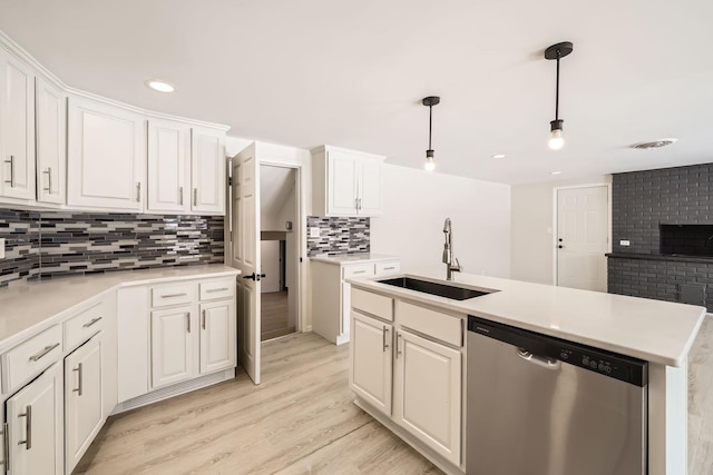 kitchen featuring tasteful backsplash, light wood-style floors, white cabinets, a sink, and dishwasher