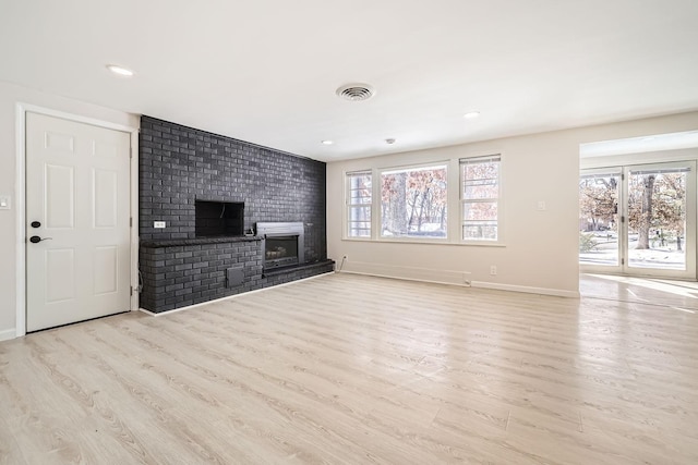 unfurnished living room with a brick fireplace, wood finished floors, visible vents, and baseboards