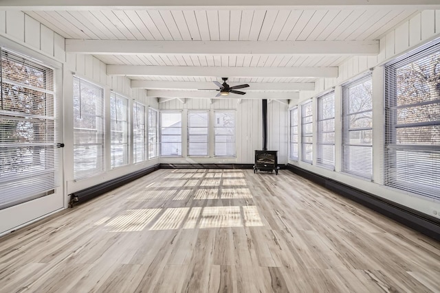 unfurnished sunroom with a baseboard radiator, a wood stove, ceiling fan, and beam ceiling