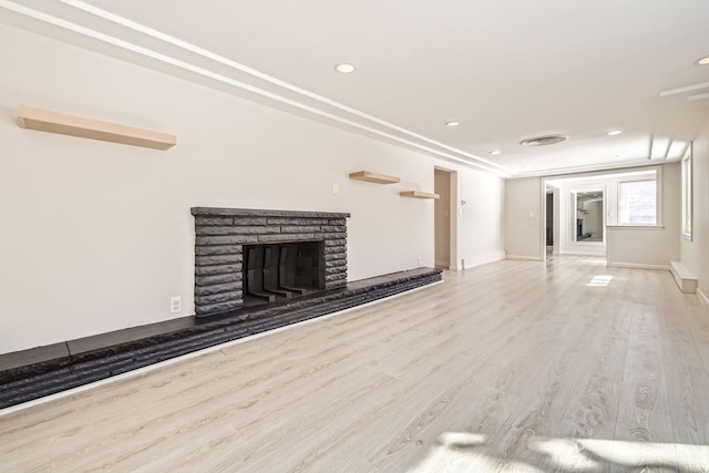 unfurnished living room featuring recessed lighting, a fireplace with raised hearth, baseboards, and wood finished floors