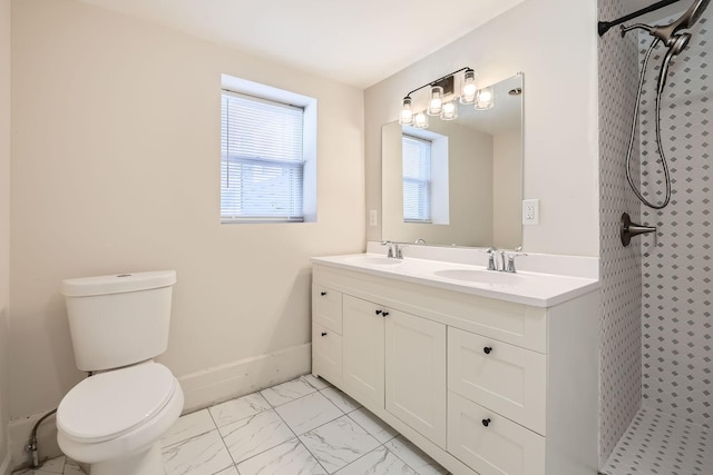 bathroom featuring marble finish floor, tiled shower, a sink, and toilet