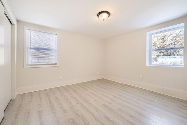 empty room with plenty of natural light, baseboards, and wood finished floors