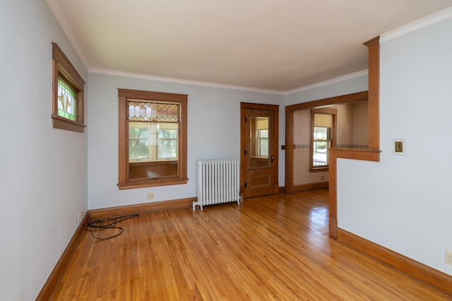 spare room with baseboards, crown molding, light wood-style flooring, and radiator heating unit