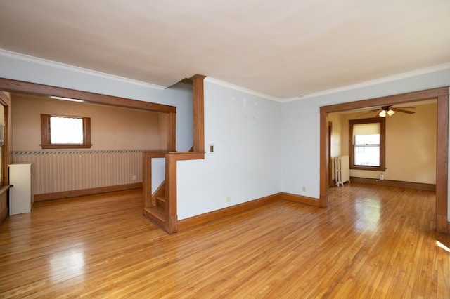 spare room with radiator, stairway, light wood-style flooring, and ornamental molding