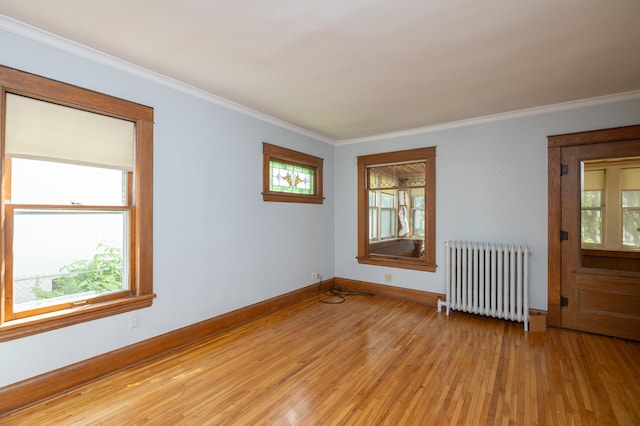 unfurnished room with light wood-style floors, radiator heating unit, baseboards, and crown molding