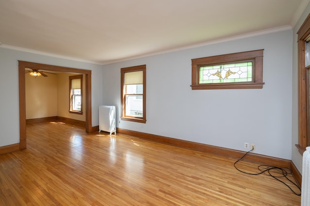 spare room featuring ornamental molding, light wood-type flooring, a wealth of natural light, and radiator